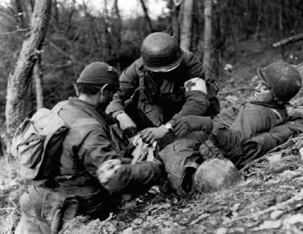 Sanitarios atendiendo a un soldado herido de la 4ª División de Infantería. 18 noviembre 1944